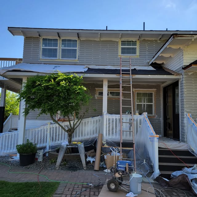 Two-story home exterior being prepped with scaffolding and masking tarps before paint